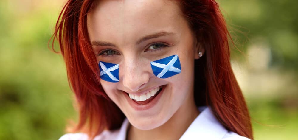 happy female with scottish flags on her cheeks e1619177639518