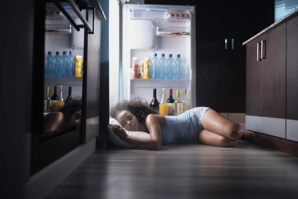 woman sleeping by refrigerator
